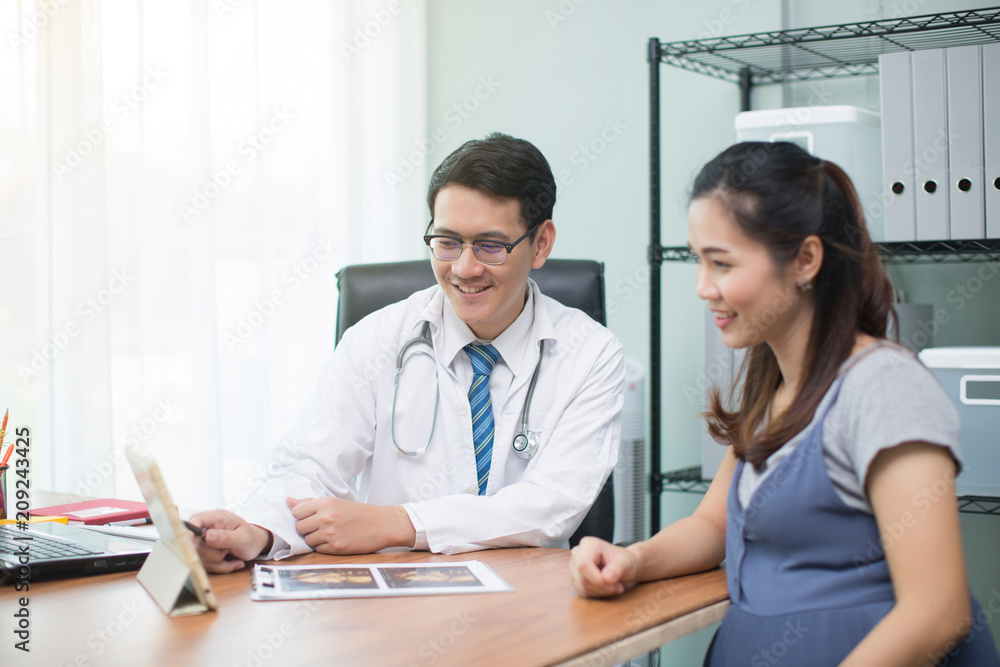 Pregnant woman talking to her doctor in a room Pregnant woman talking to her doctor in a room