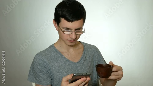 guy uses a smartphone and drinks coffee