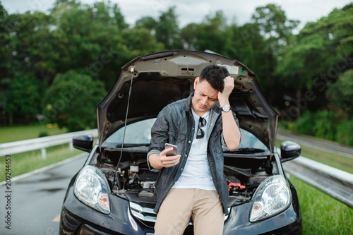 Young Asia man having trouble with his broken car,Using smart phone