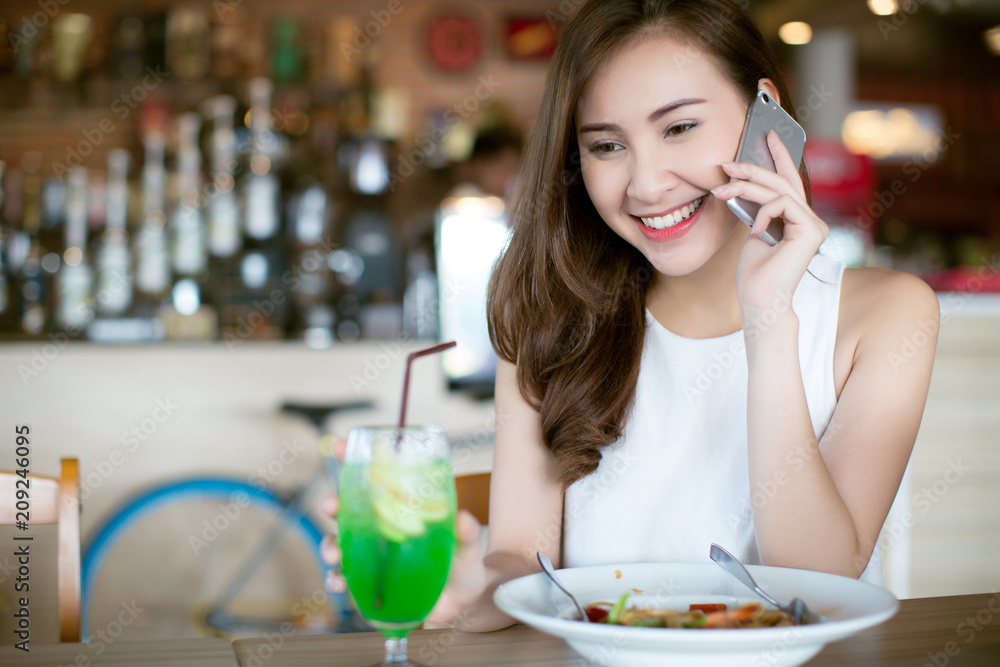 Portrait of pretty woman talking on the phone while sitting in the cafe and enjoying the food Portrait of pretty woman talking on the phone while sitting in the cafe and enjoying the food