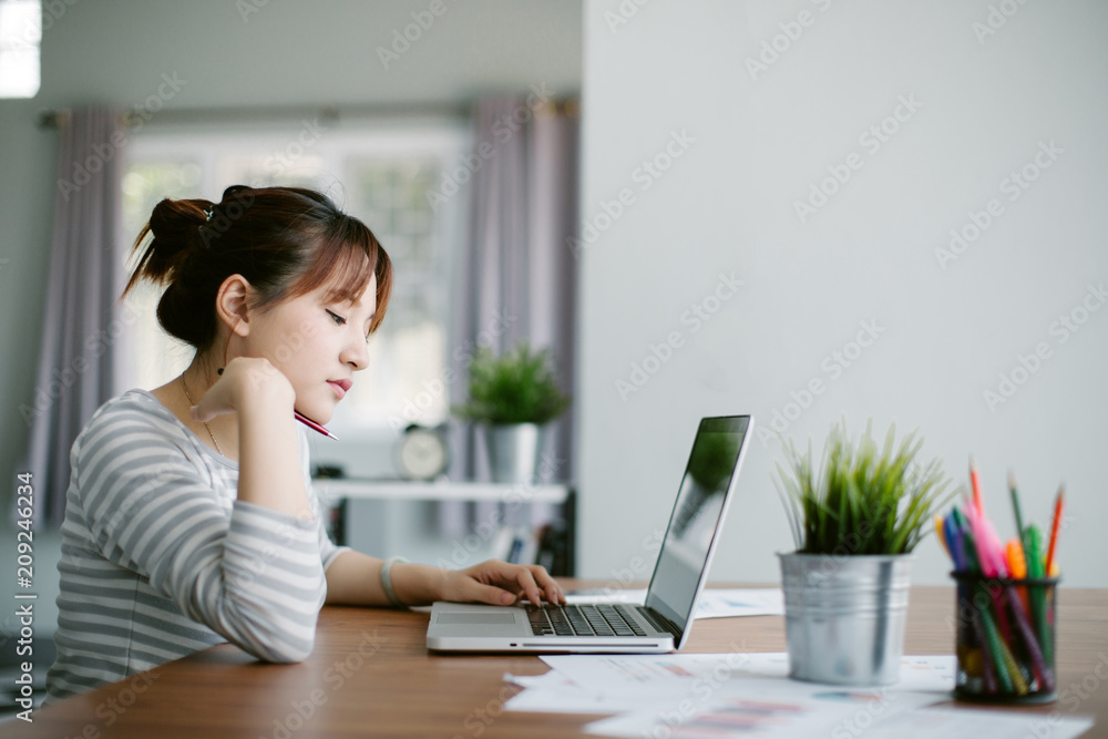 Beautiful young Asia woman working with laptop in living room Beautiful young Asia woman working with laptop in living room