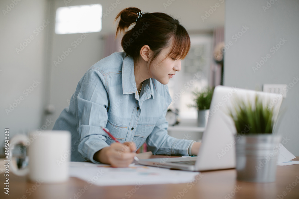 Beautiful young Asia woman working with laptop in living room Beautiful young Asia woman working with laptop in living room
