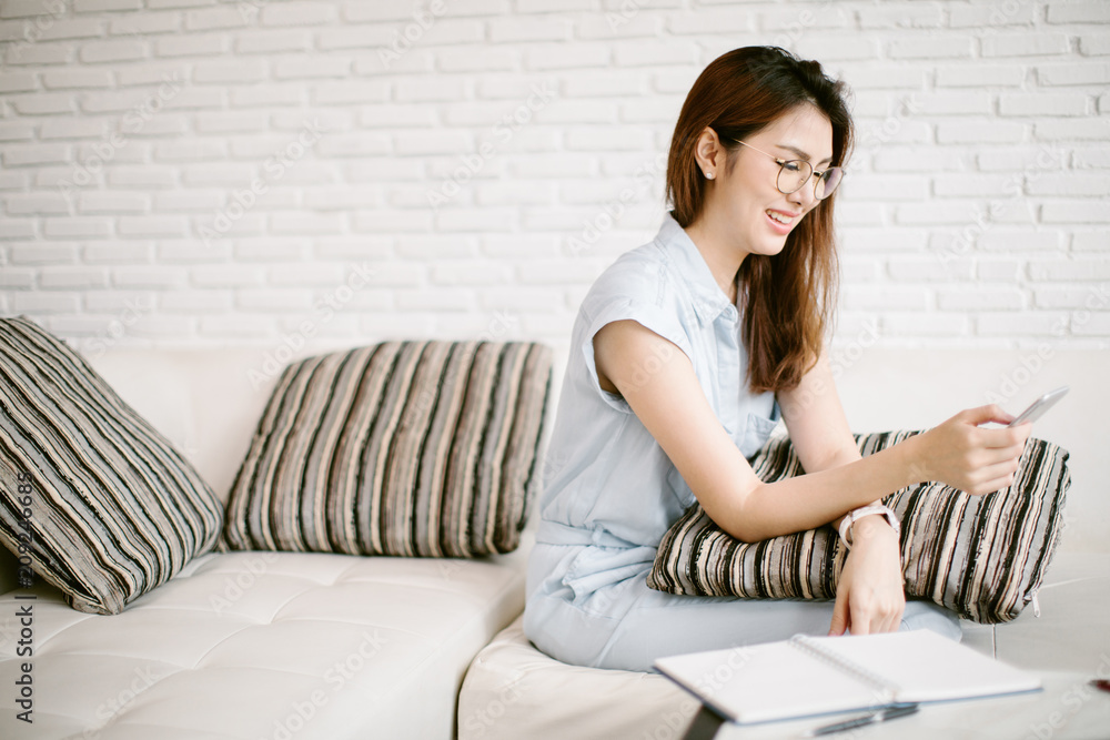 Beautiful young Asia woman working with smart phone in living room Beautiful young Asia woman working with smart phone in living room