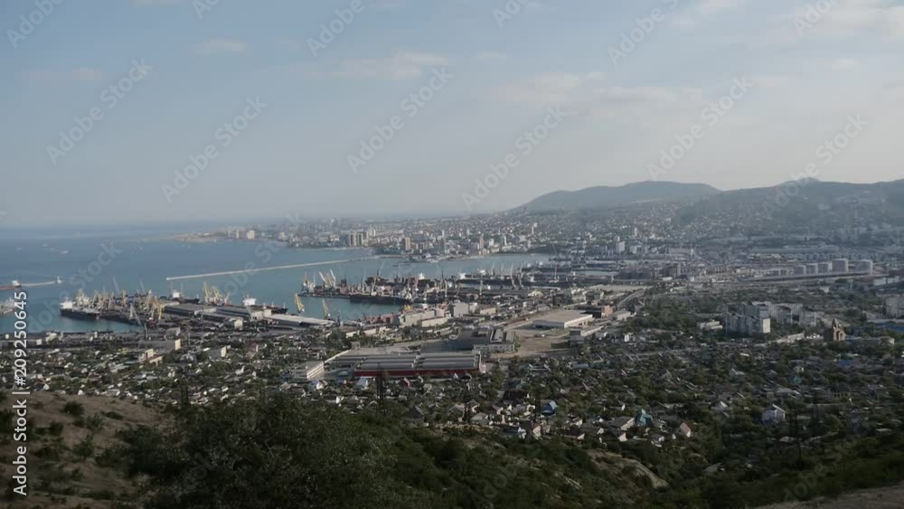 NOVOROSSIYSK, RUSSIA - CIRCA 2018: View of seaside resort, port city from skyscraper window. View of seaport city from bird's eye view. Beautiful summer city landscape from window of new building NOVOROSSIYSK, RUSSIA - CIRCA 2018: View of seaside resort, port city from skyscraper window. View of seaport city from bird's eye view. Beautiful summer city landscape from window of new building