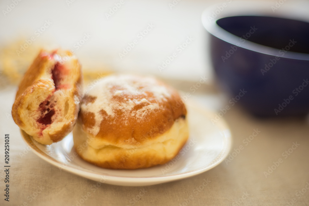 donuts in a saucer on a table with a mug of tea