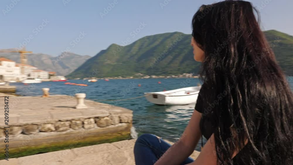 A young woman on the background of a sea bay and a mountain chain. A young woman on the background of a sea bay and a mountain chain.