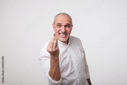 Bald handsome mature man looking angry showing italian gesture over white background. © Viktor Koldunov