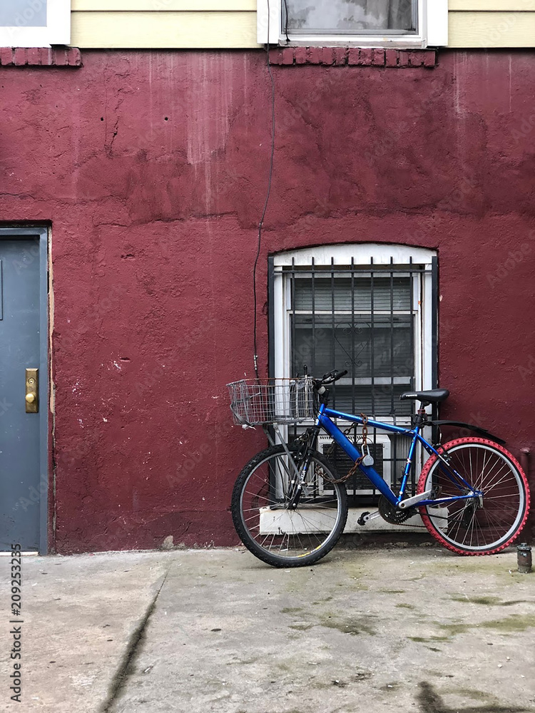 Blue bike leaning against a red wall