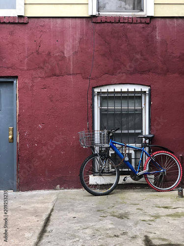 Blue bike leaning against a red wall © Rebecca