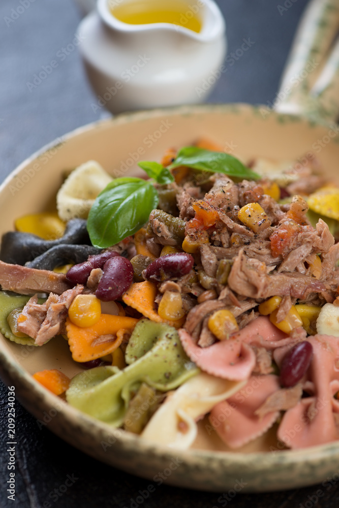Close-up of multicolored farfalle pasta with tuna fillet, selective focus, vertical shot