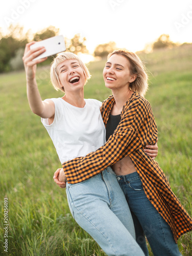 Two young women shoot photos of themselfs on mobile phone. Best friends photo