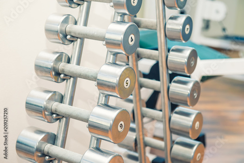 Rows of metal heavy dumbbells on stand in sport gym, physiotherapy clinic. Physical therapy center. Sports equipment for training. Selective focus. copy space.