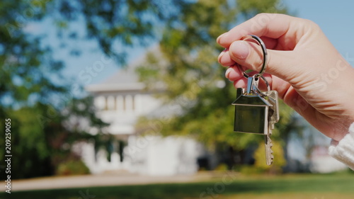 The hand holds the key to the house. Rent and purchase of housing concept
