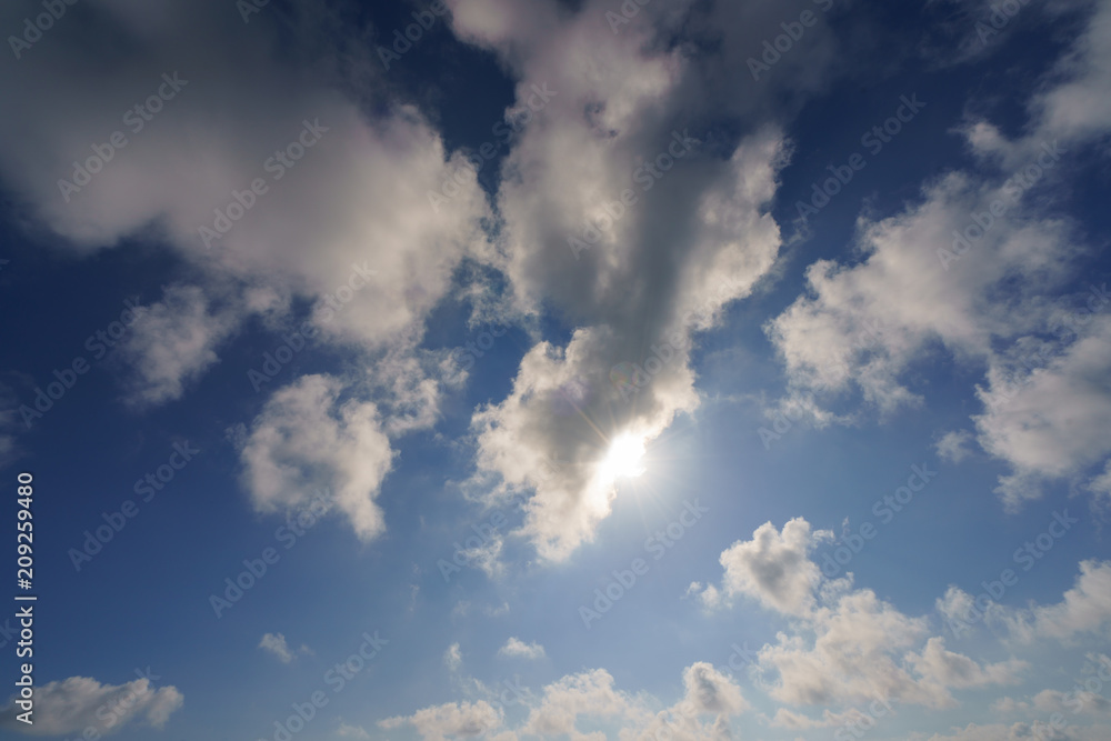 Fototapeta premium Bright and high summer sky. The sun makes its way through the clouds. Backlit image. Backlit image.