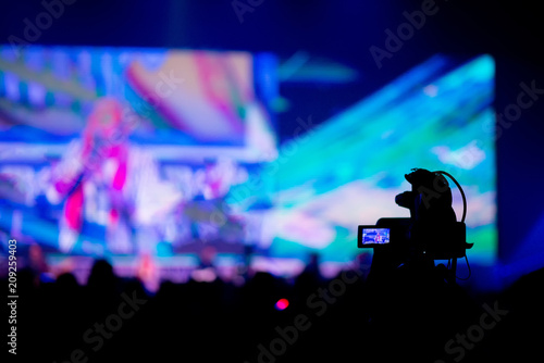 Video Camera shooting crowd in Concert Hall.Camcorder recording news at night event party by journalist or videographer.Camcorder and technology Concept