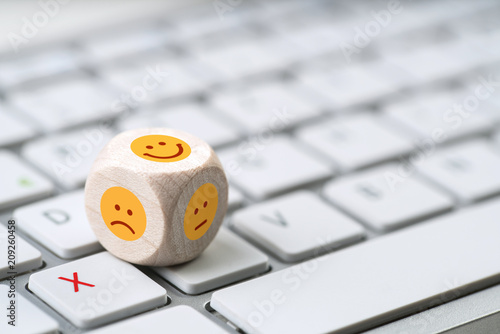 verschiedene Emoticons auf einem Würfel der auf einer Tastatur liegt