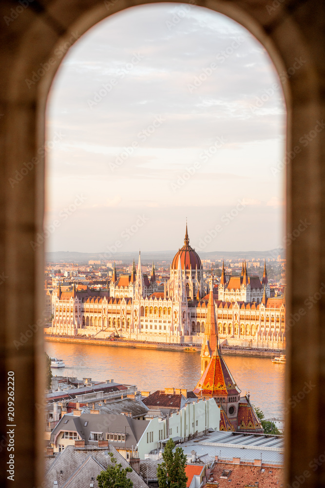 Naklejka premium Cityscape widok przez łuk na słynnym budynku Parlamentu w świetle słońca w Budapeszcie na Węgrzech