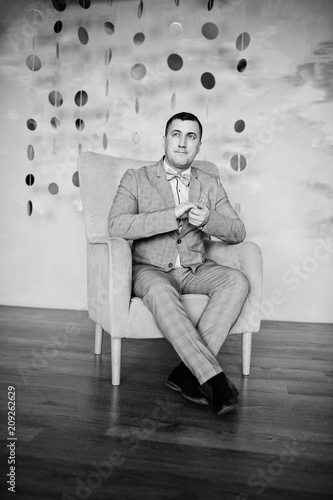Studio portrait of man in suit near chair. © AS Photo Family
