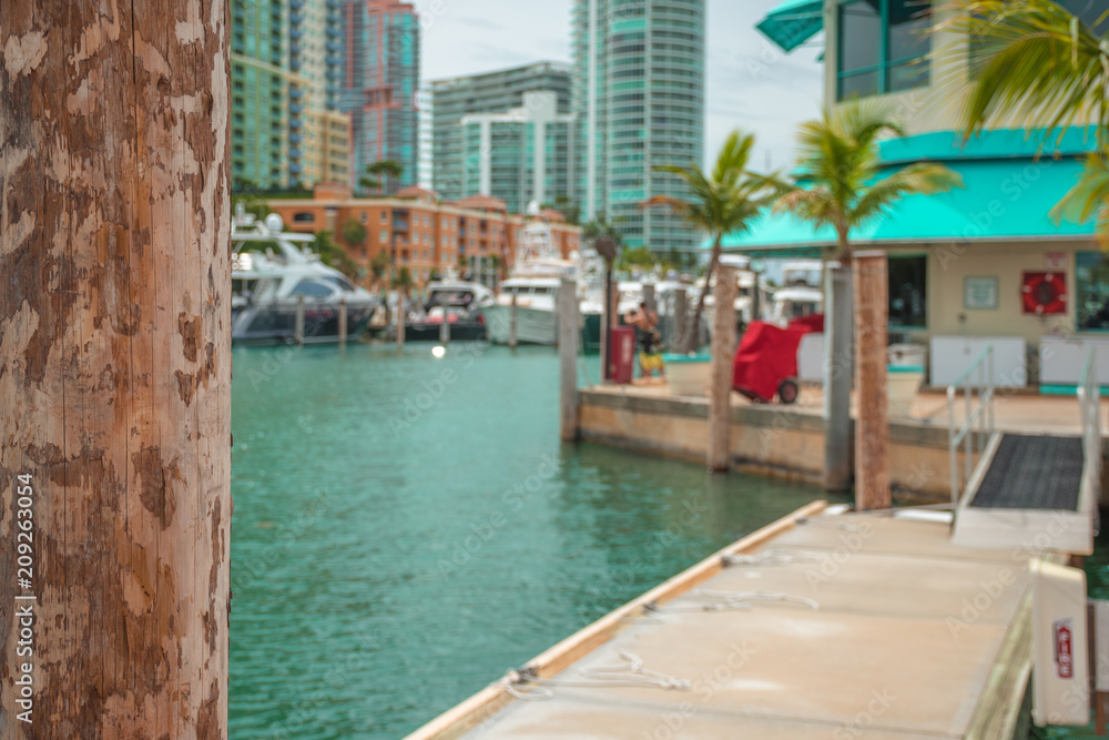 Wooden post. Expensive, luxurious yachts and tall buildings in the background. Miami, Florida, USA