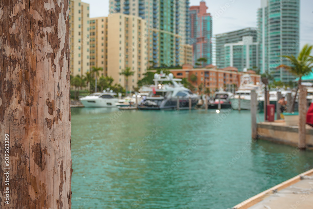 Wooden post. Expensive, luxurious yachts and tall buildings on the background.