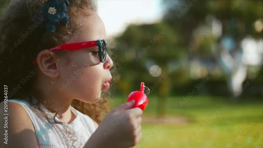 Happy child blowing soap bubbles in park. Slow motion. Stock footage. Happy child blowing soap bubbles in park. Slow motion. Stock footage.