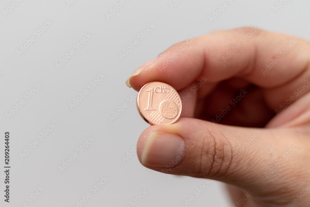 Euro Cent zwischen den Fingern einer Frau vor weißer Wand Euro Cent zwischen den Fingern einer Frau vor weißer Wand
