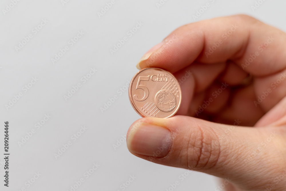 Five cent coin between the fingers of a woman Five cent coin between the fingers of a woman