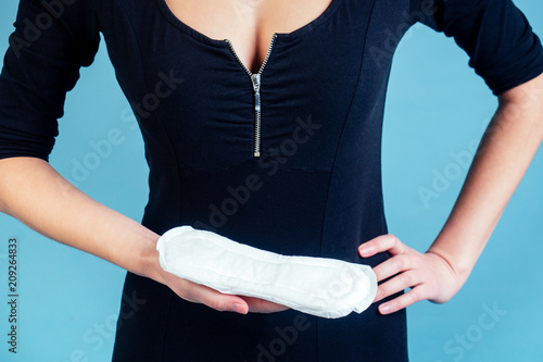 white sanitary napkin in the hands of a girl on a blue background (Concept pms and monthly)
