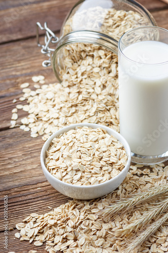 Oatmeal flakes and glass of milk on wooden table.