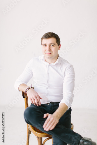 Portrait of handsome man in white skirt and black trousers and looking at camera, isolated on white