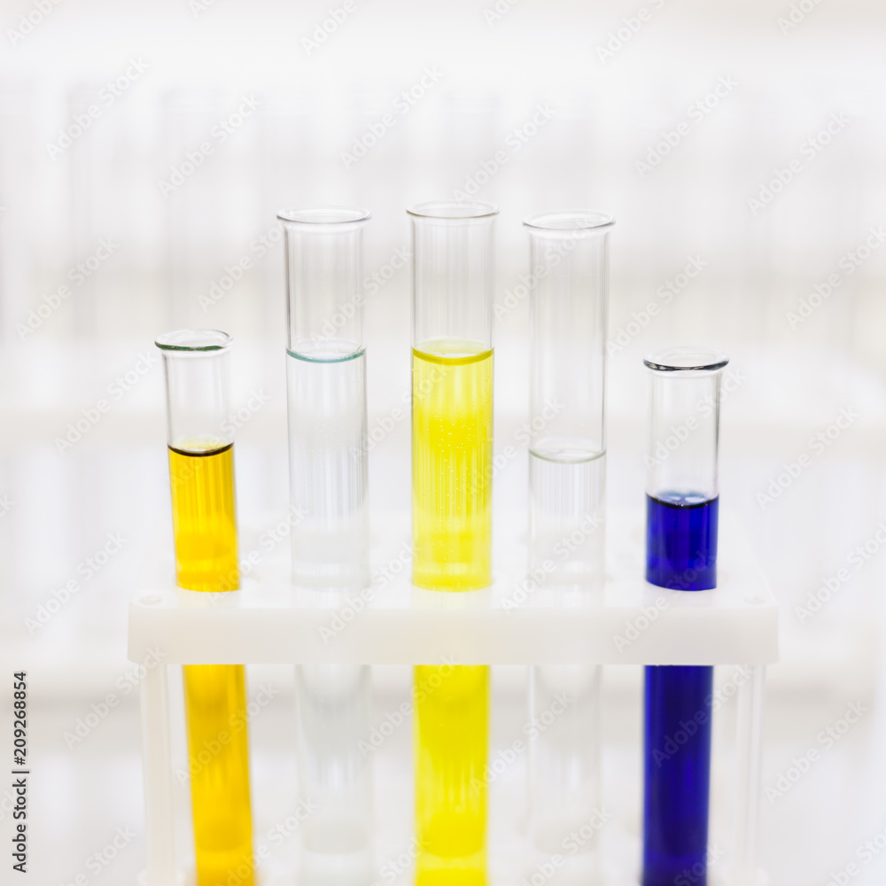 Glass tubes with color reagents stand in a laboratory tripod. Soft focus. Medical and scientific research and development concept. A square photo. Glass tubes with color reagents stand in a laboratory tripod. Soft focus. Medical and scientific research and development concept. A square photo.