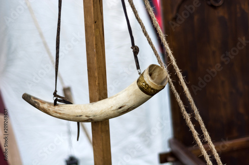Medieval horn for alert hanging on wooden stand. Middle ages life concept. Close up, selective focus