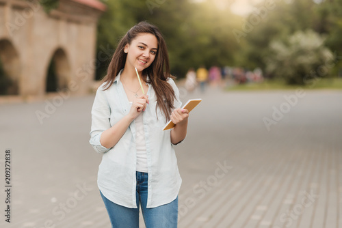 A young girl with a notebook and a pen in her hand is solving her homework. writes notes to notepad