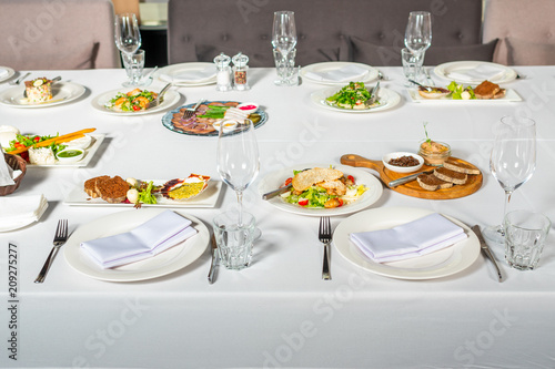 Served table in a restaurant with cold snacks. Place setting at laid restaurant banquet table.