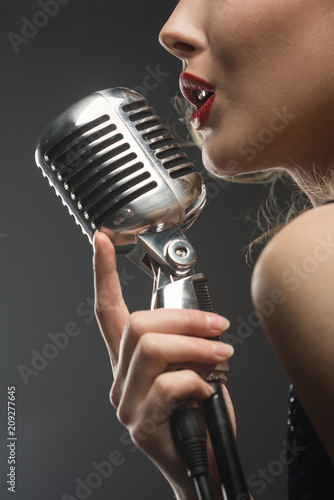 Portreit of sexy young girl singer singing with silver retro microphone