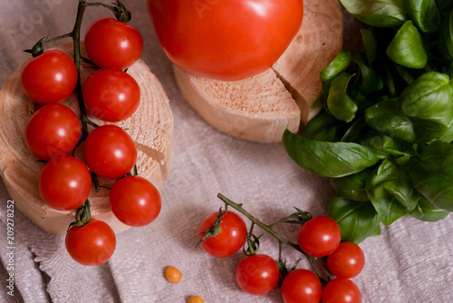 Caesar salad with white mozzarella cheese and cherry tomatoes, fresh basilon a gray linen napkin. wooden table, copy space photo