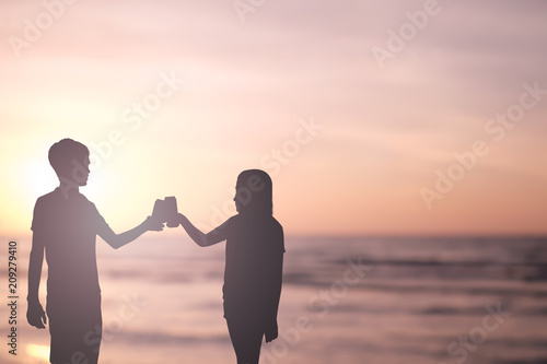 silhouette of couple lover shooting glass of beer together at sea beach on married anniversary conceptt