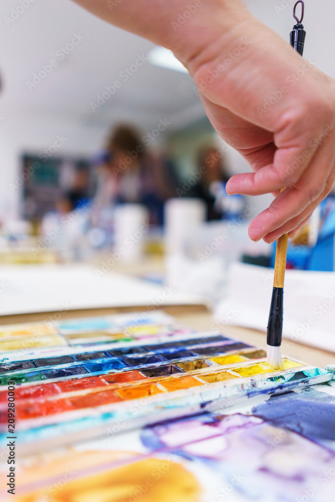 Artist makes the first brush strokes on a clean canvas while painting a watercolor painting. Artist makes the first brush strokes on a clean canvas while painting a watercolor painting.