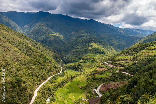 Aerial drone view of huge rice terraces in a valley surrounded by tall mountains and low hanging cloud (Banaue)