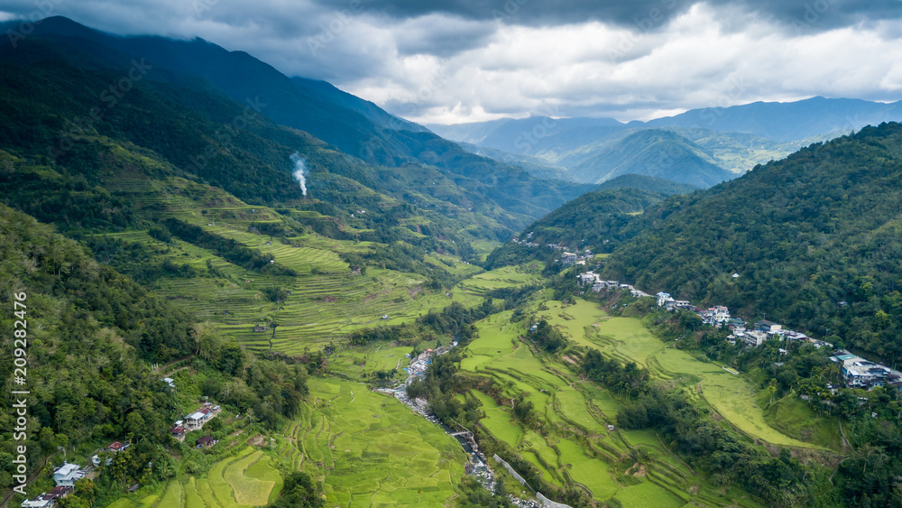 Panoramic aerial drone view of beautiful rice terraces surrounded by tall mountains and low cloud