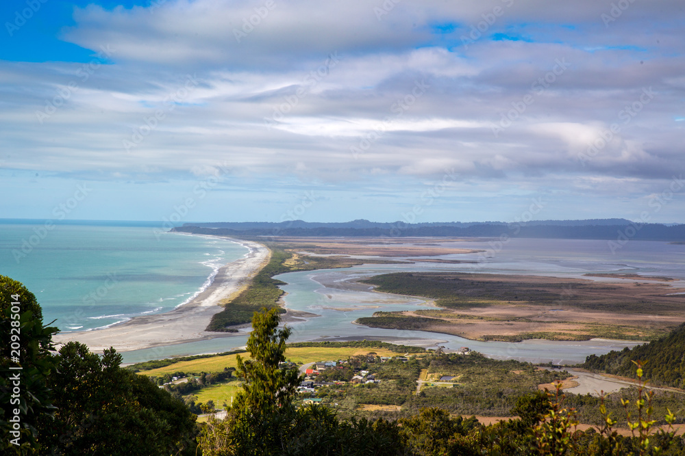 Landscape view over the ocean and estuary from a hill above Okarito, West Coast, New Zealand Landscape view over the ocean and estuary from a hill above Okarito, West Coast, New Zealand