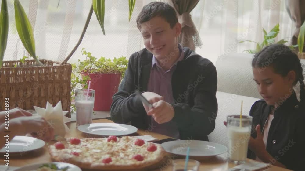 boy teen and girls eats pizza in cafe slow motion video. children eat pizza a delicious pizza. company of people friends lifestyle eating in a cafe. kids eating pizza lifestyle concept boy teen and girls eats pizza in cafe slow motion video. children eat pizza a delicious pizza. company of people friends lifestyle eating in a cafe. kids eating pizza lifestyle concept