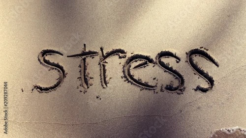 Stress handwritten in the sand washed away by a slow motion wave