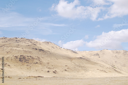 Landscape with dry land and blue cloudy sky