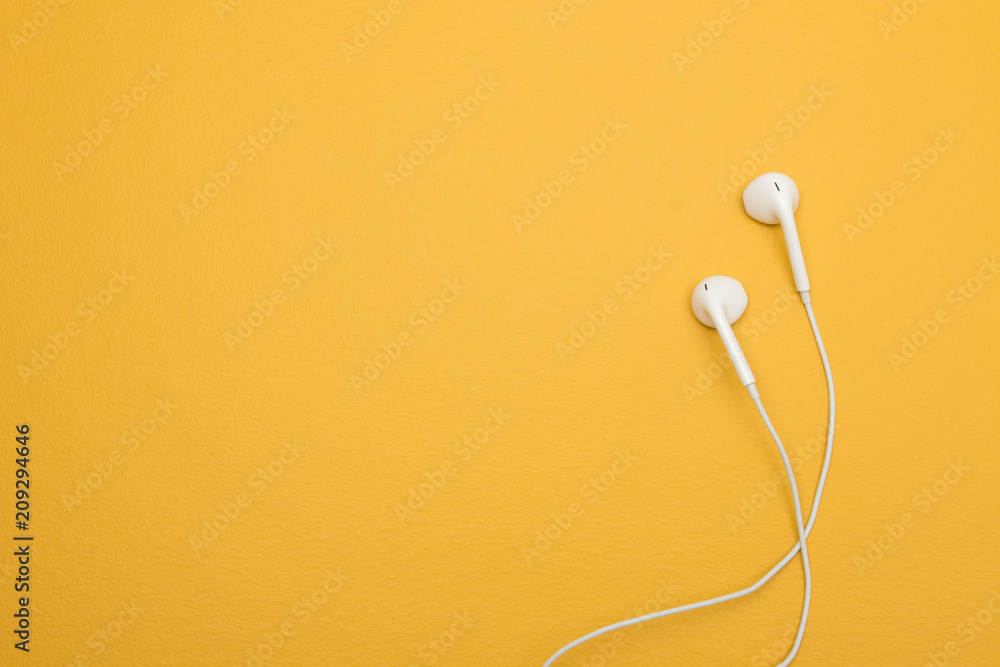 Naklejka premium Białe słuchawki na żółtym tle z miejsca na kopię