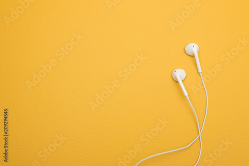 White earphones on yellow background with copy space photo