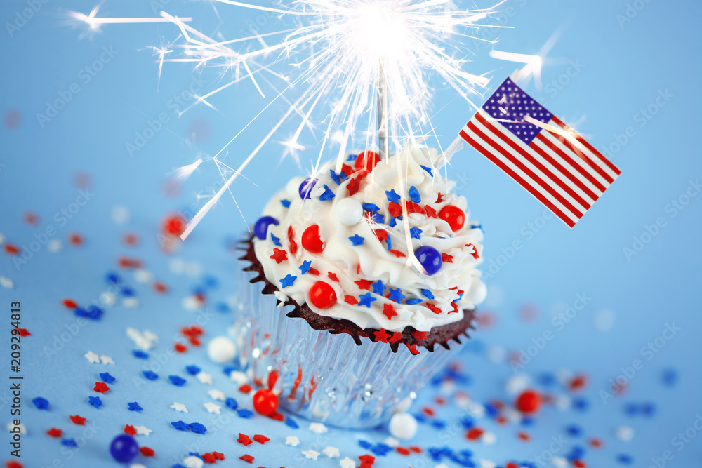 Obraz premium 4th of July cupcake with flag, sprinkles, and sparkler