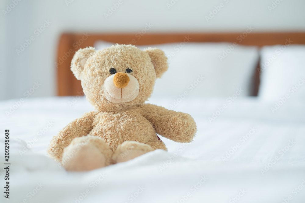 Cute little teddy bear sitting alone on white bed in morning. Cute little teddy bear sitting alone on white bed in morning.