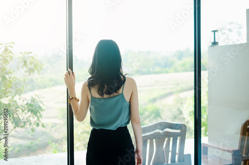 Lonely young woman standing in room looked out of the window. photo