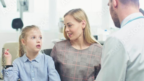 Mother with Sweet Little Girl Visit Friendly Pediatrician. Scared Child Talks about Fear of Needles but Professional Doctor Calms Her Down. Brightand Modern Medical Office. photo